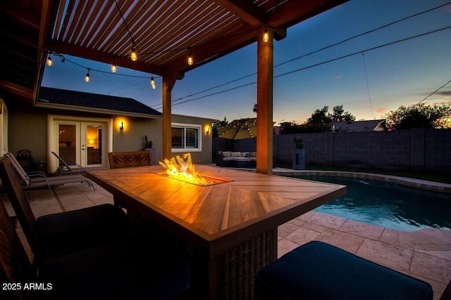 pool at dusk featuring an outdoor living space with a fire pit, a pergola, french doors, and a patio