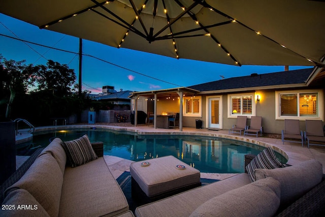 pool at dusk with a patio and outdoor lounge area