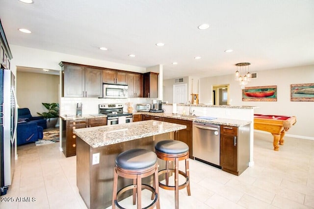 kitchen featuring stainless steel appliances, pool table, a center island, and kitchen peninsula