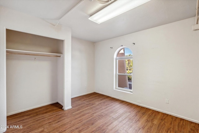 unfurnished bedroom with wood-type flooring and a closet