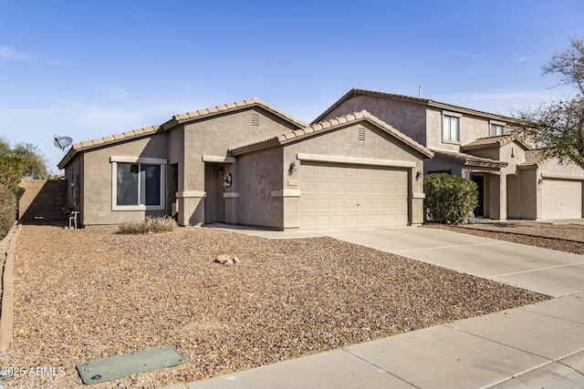 view of front facade with concrete driveway, an attached garage, a tiled roof, and stucco siding