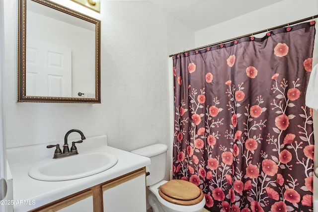 bathroom with curtained shower, vanity, and toilet