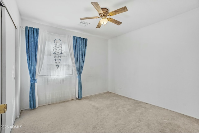 spare room with visible vents, a ceiling fan, and light colored carpet