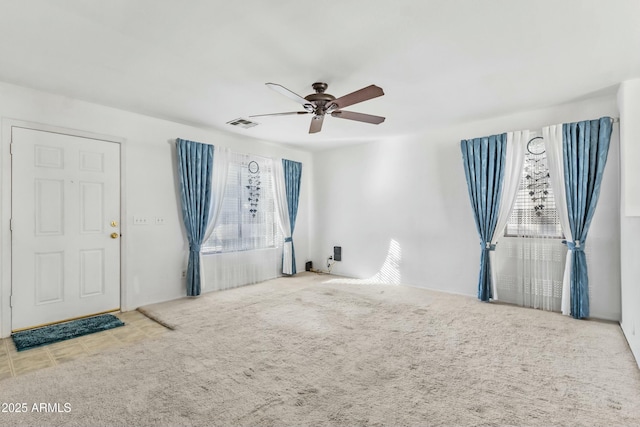 empty room featuring light carpet, ceiling fan, and visible vents