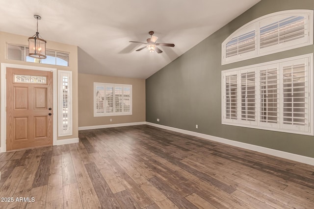 foyer entrance featuring ceiling fan with notable chandelier, dark hardwood / wood-style flooring, and vaulted ceiling