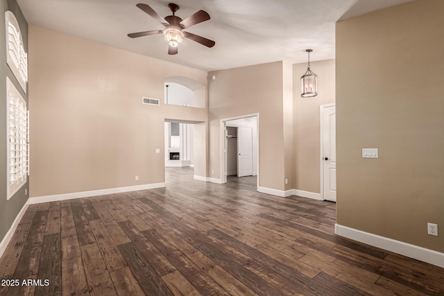 unfurnished living room featuring high vaulted ceiling, dark hardwood / wood-style floors, ceiling fan, and plenty of natural light