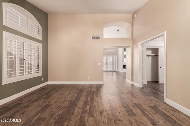 empty room with french doors, dark hardwood / wood-style floors, and a high ceiling