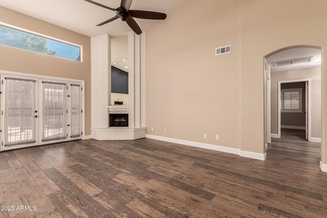 unfurnished living room with ceiling fan, a fireplace, dark hardwood / wood-style flooring, and high vaulted ceiling