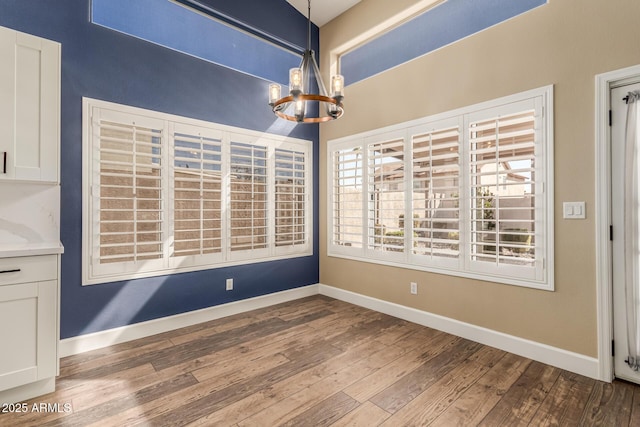 unfurnished dining area with hardwood / wood-style flooring and a notable chandelier