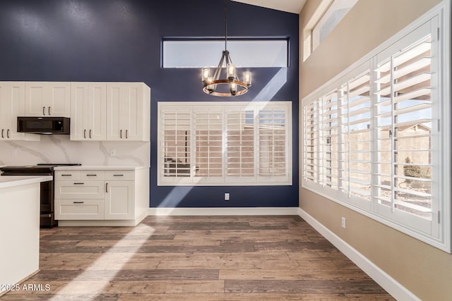 kitchen featuring white cabinetry, hanging light fixtures, electric range, dark hardwood / wood-style floors, and a notable chandelier