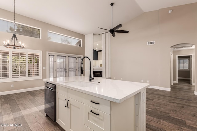 kitchen with pendant lighting, sink, white cabinetry, light stone countertops, and a center island with sink