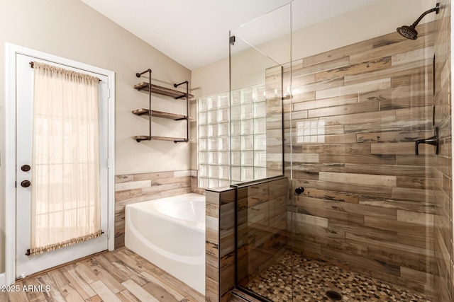 bathroom with independent shower and bath, wood-type flooring, and tile walls