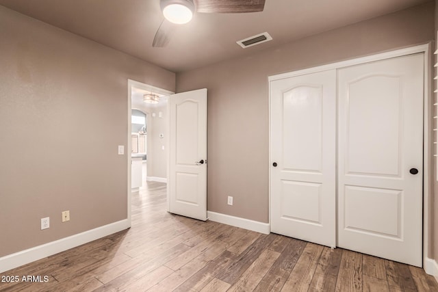 unfurnished bedroom featuring ceiling fan, a closet, and light wood-type flooring