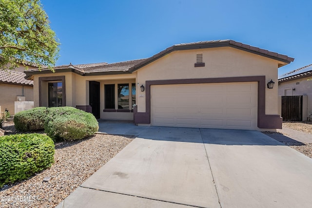 ranch-style house with a garage, a tile roof, driveway, and stucco siding
