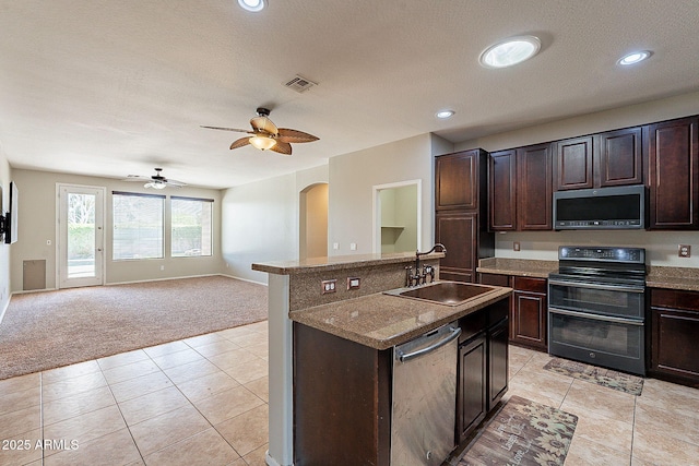 kitchen featuring a sink, arched walkways, light carpet, appliances with stainless steel finishes, and visible vents