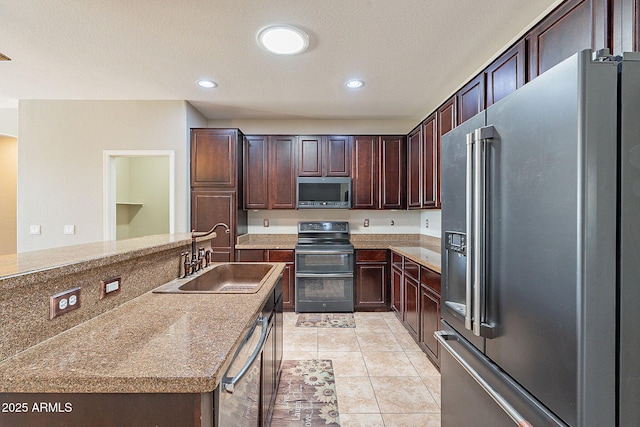 kitchen with light countertops, light tile patterned floors, a sink, dark brown cabinetry, and appliances with stainless steel finishes