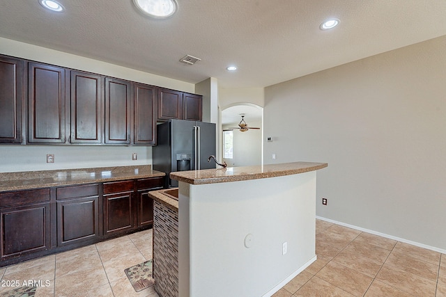kitchen with visible vents, light tile patterned flooring, black fridge with ice dispenser, a kitchen island with sink, and ceiling fan