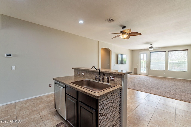 kitchen featuring arched walkways, a sink, open floor plan, ceiling fan, and dishwasher
