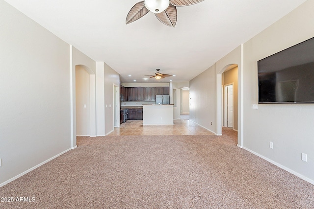 unfurnished living room with recessed lighting, a ceiling fan, light carpet, arched walkways, and baseboards