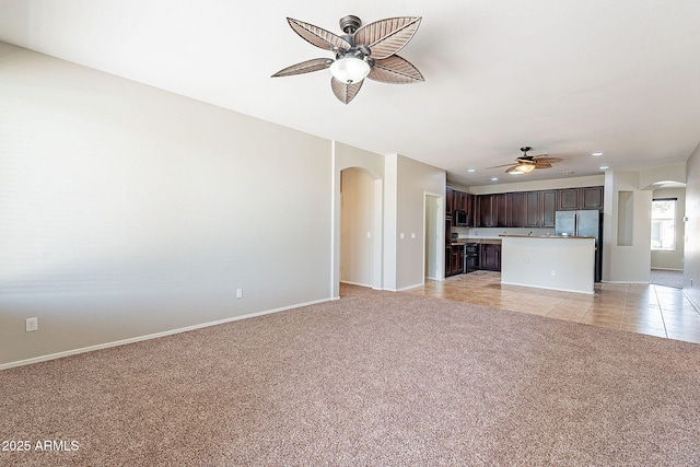 unfurnished living room featuring a ceiling fan, arched walkways, recessed lighting, and light colored carpet
