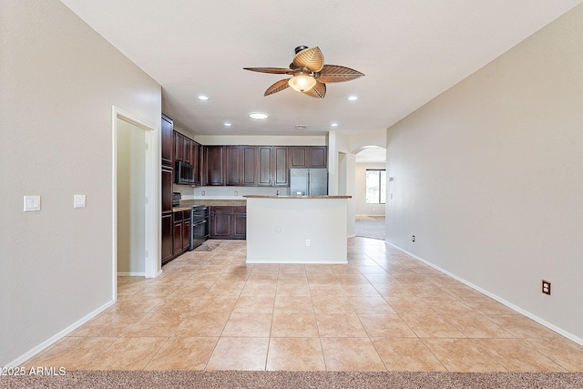 kitchen featuring arched walkways, dark brown cabinets, light tile patterned floors, ceiling fan, and appliances with stainless steel finishes