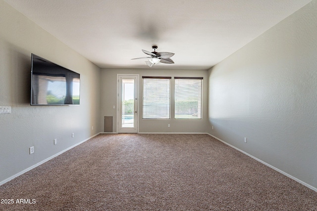carpeted spare room with a ceiling fan and baseboards