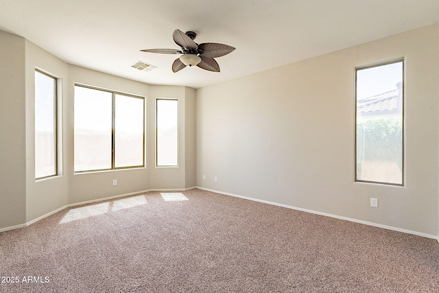 carpeted spare room with baseboards, a ceiling fan, and visible vents