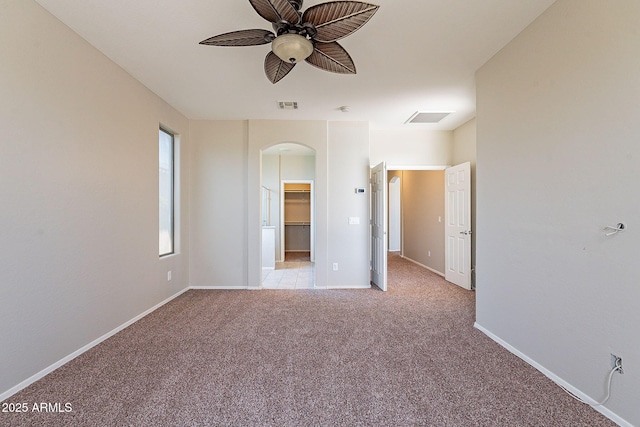 unfurnished bedroom featuring light carpet, baseboards, visible vents, and arched walkways