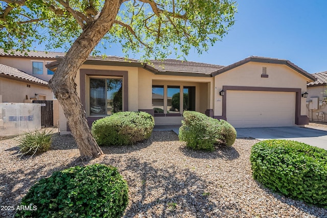 view of front of home featuring concrete driveway, a tiled roof, fence, a garage, and stucco siding