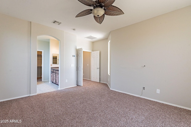 unfurnished bedroom with baseboards, arched walkways, visible vents, and light carpet