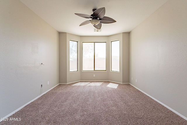 carpeted spare room featuring baseboards, a ceiling fan, and visible vents