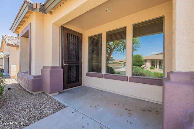 entrance to property with a tiled roof and stucco siding