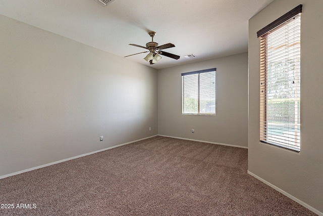 carpeted empty room featuring baseboards, a ceiling fan, and visible vents