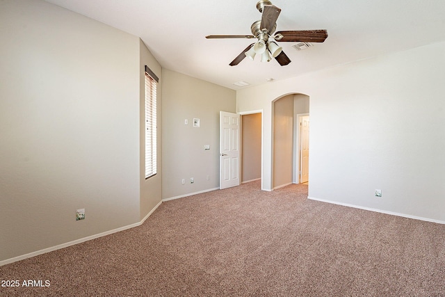unfurnished room with arched walkways, a ceiling fan, baseboards, and light carpet