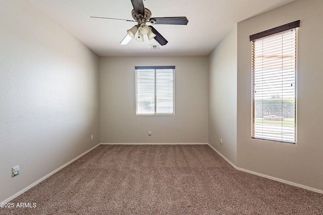 spare room with carpet floors, a ceiling fan, visible vents, and plenty of natural light
