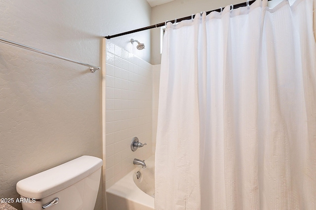 bathroom featuring shower / bath combination with curtain, toilet, and a textured wall
