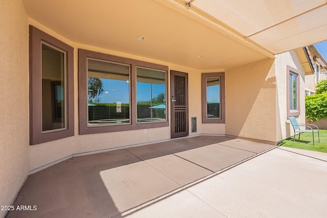 view of exterior entry with a patio area and stucco siding
