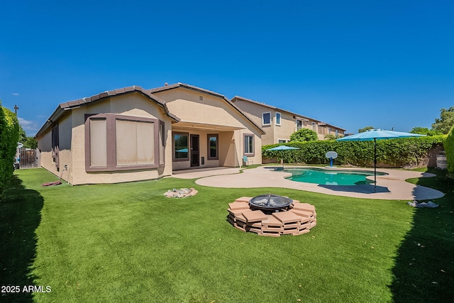 rear view of property with a patio area, a lawn, a fire pit, and stucco siding