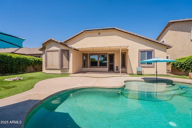 back of property with a fenced in pool, a tiled roof, a yard, stucco siding, and a patio area