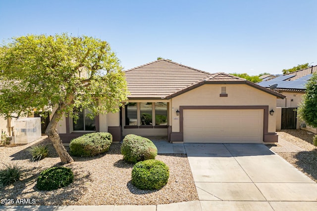 view of front of home featuring a garage, driveway, a tiled roof, and stucco siding