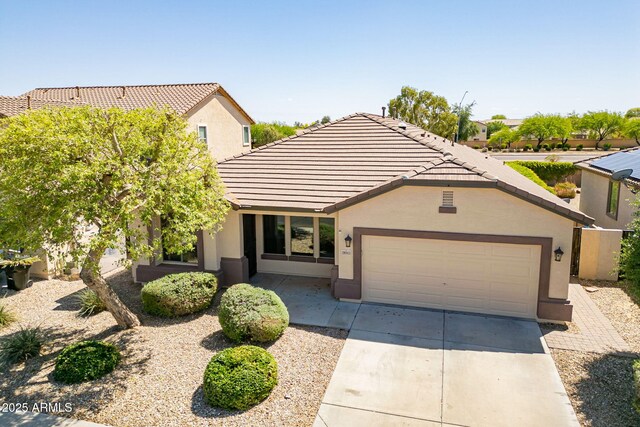 view of front of property featuring stucco siding, an attached garage, concrete driveway, and a tiled roof