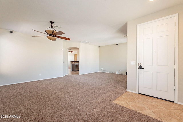 unfurnished room with ceiling fan, arched walkways, light carpet, baseboards, and visible vents