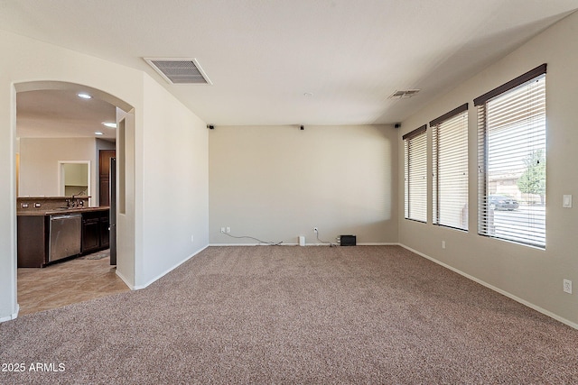 unfurnished room with light colored carpet, arched walkways, visible vents, and baseboards