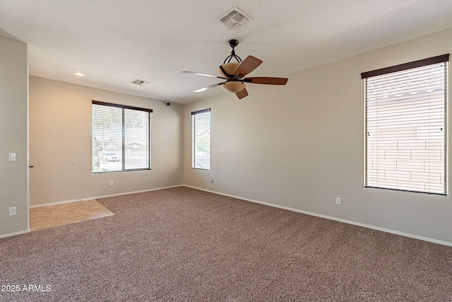 carpeted empty room featuring baseboards, visible vents, and ceiling fan