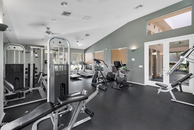 gym featuring plenty of natural light, a ceiling fan, vaulted ceiling, and baseboards