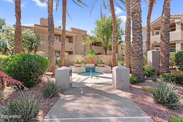 surrounding community with fence, a hot tub, and a patio area