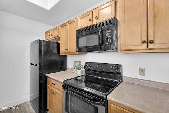 kitchen featuring black appliances, light brown cabinets, light countertops, baseboards, and wood finished floors
