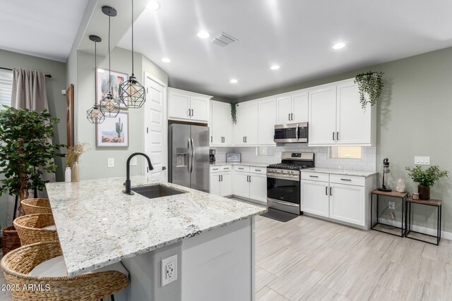 19414 W Highland Ave, Litchfield Park, AZ 85340 - kitchen featuring a breakfast bar area, tasteful backsplash, light stone counters, a sink, and appliances with stainless steel finishes