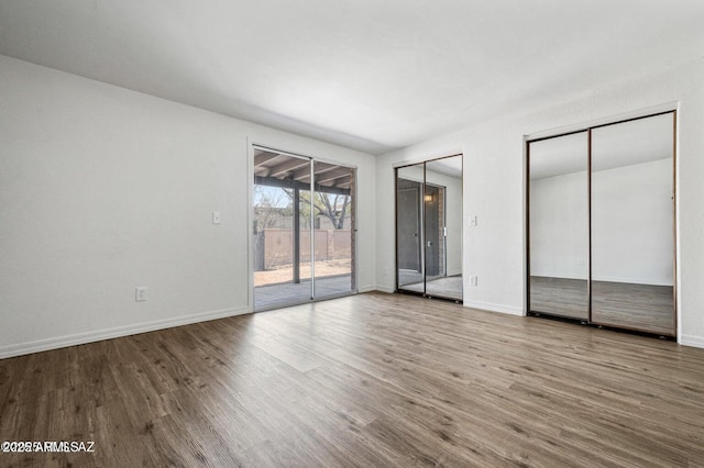 8118 N Gibraltar Dr, Tucson, AZ 85704 - unfurnished bedroom featuring baseboards, access to outside, two closets, and wood finished floors
