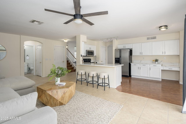 25825 N 65th Ave, Phoenix, AZ 85083 - living area featuring arched walkways, light tile patterned flooring, visible vents, stairs, and ceiling fan